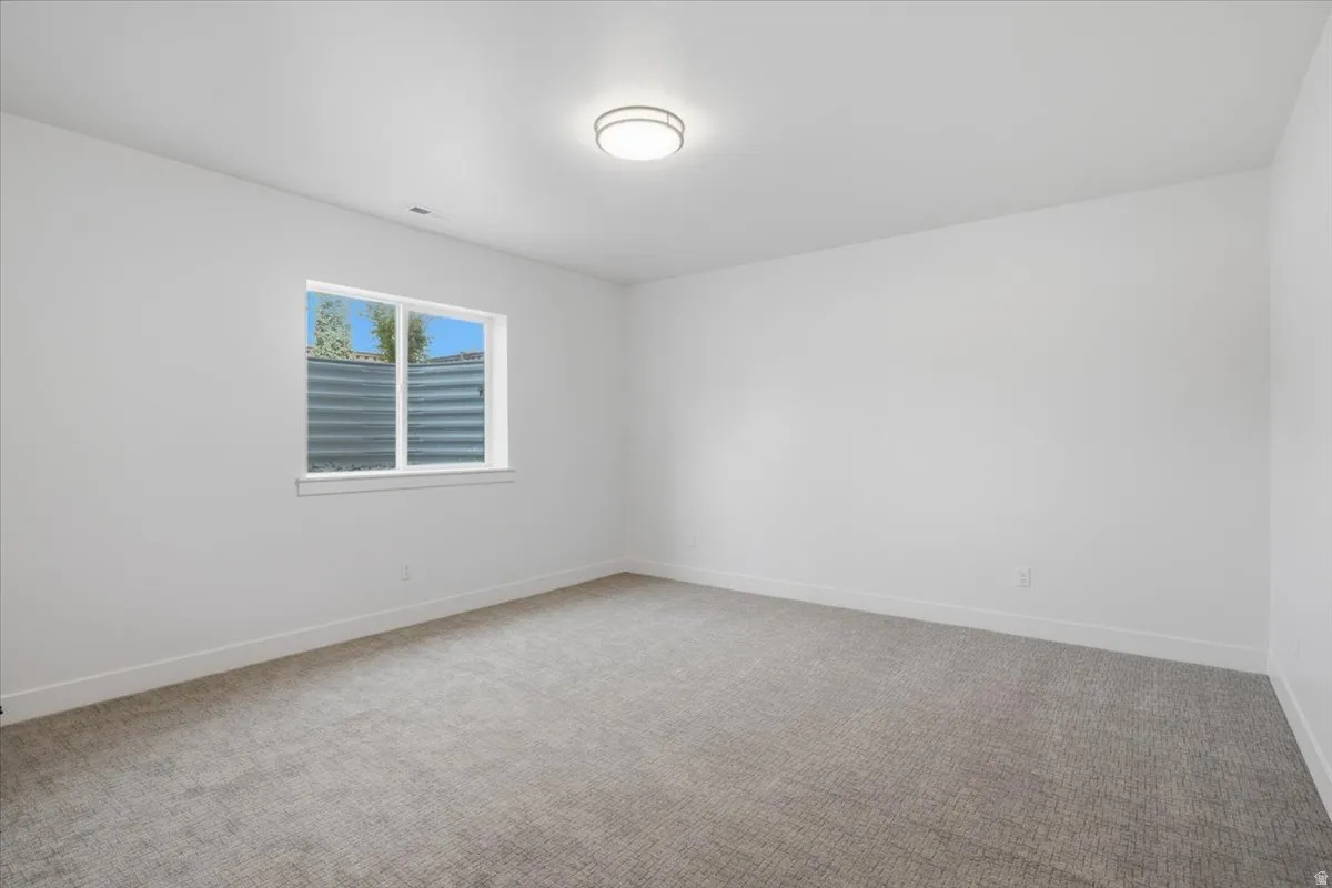 Neutral wall paint with carpet flooring, a window, and a flush mount ceiling light