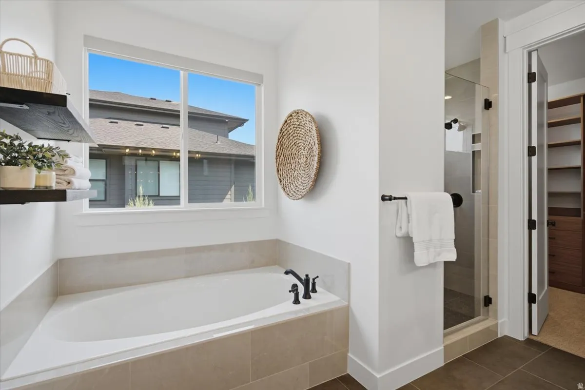 Soaking tub with a dark bronze faucet, walk-in shower with a glass enclosure, and built-in shelving