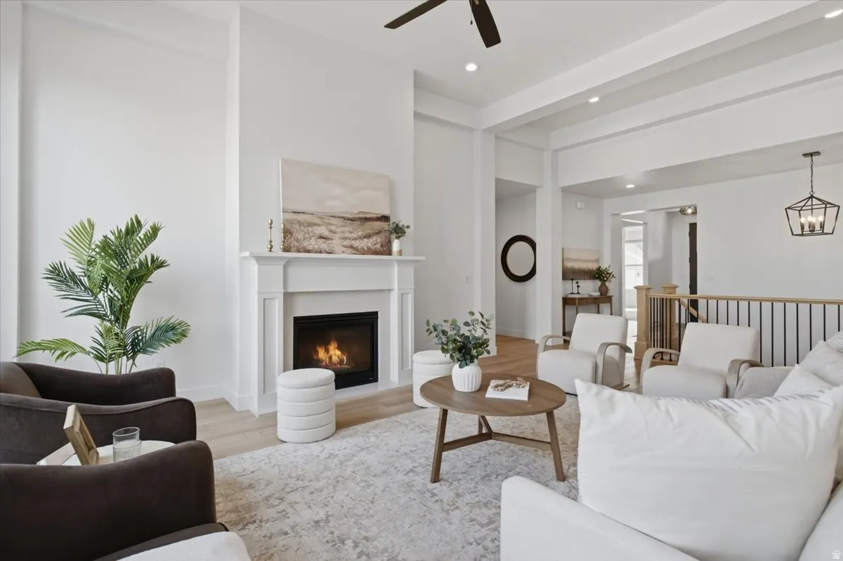 Living area with a decorative fireplace and white mantel, light wood-finish flooring, and exposed ceiling beams