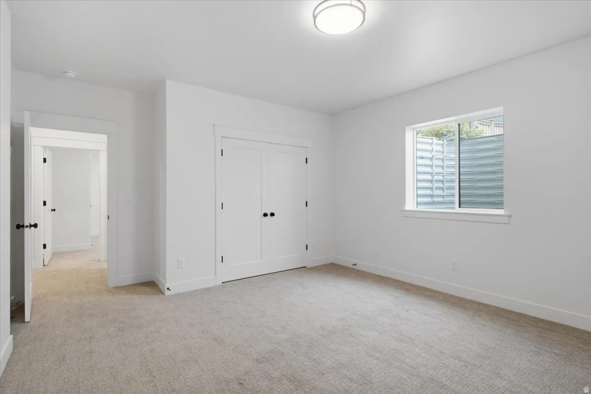 Neutral-toned carpeting, white walls, and a contemporary flush-mount ceiling light