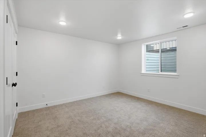 Light-toned wall-to-wall carpeting, white walls, recessed ceiling lighting, and a white-framed window