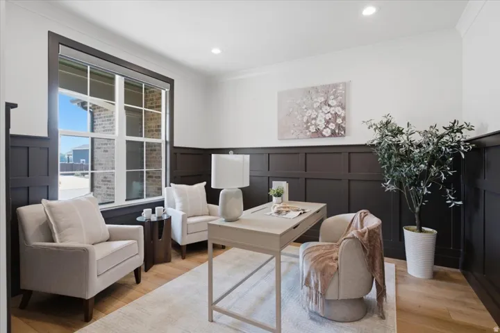 Wood-finish flooring with a decorative area rug, dark wainscoting, recessed lighting, and a large window with gridded panes