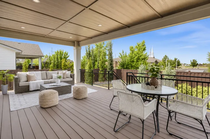 Covered outdoor deck with composite wood-finish flooring, recessed lighting, and white support columns
