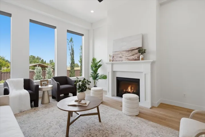 Living area featuring a classic mantel fireplace, expansive windows, wood-finish flooring, and recessed lighting