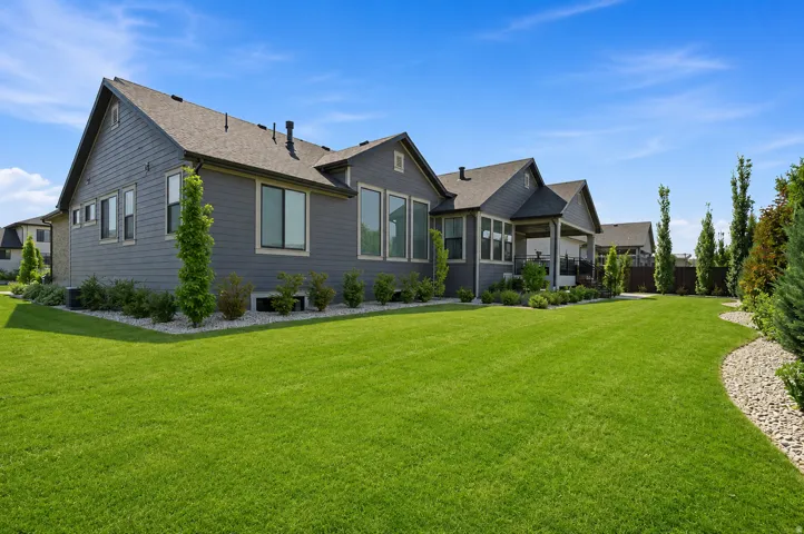 Spacious lawn area with established landscaping, featuring an exterior with dark siding and multiple large windows