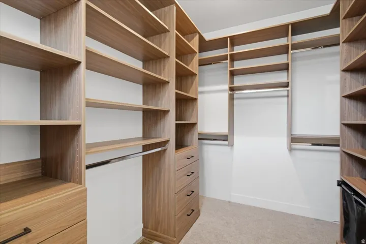 Custom closet system featuring wood-finish shelving, integrated drawers with dark hardware, and multiple hanging rods
