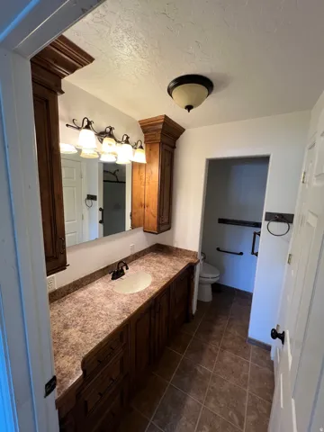 Spa-inspired master bathroom featuring dual vanity with granite countertops, rich wood cabinetry, and brushed nickel fixtures