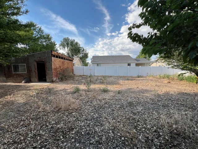 Spacious land parcel with a white privacy fence and established trees