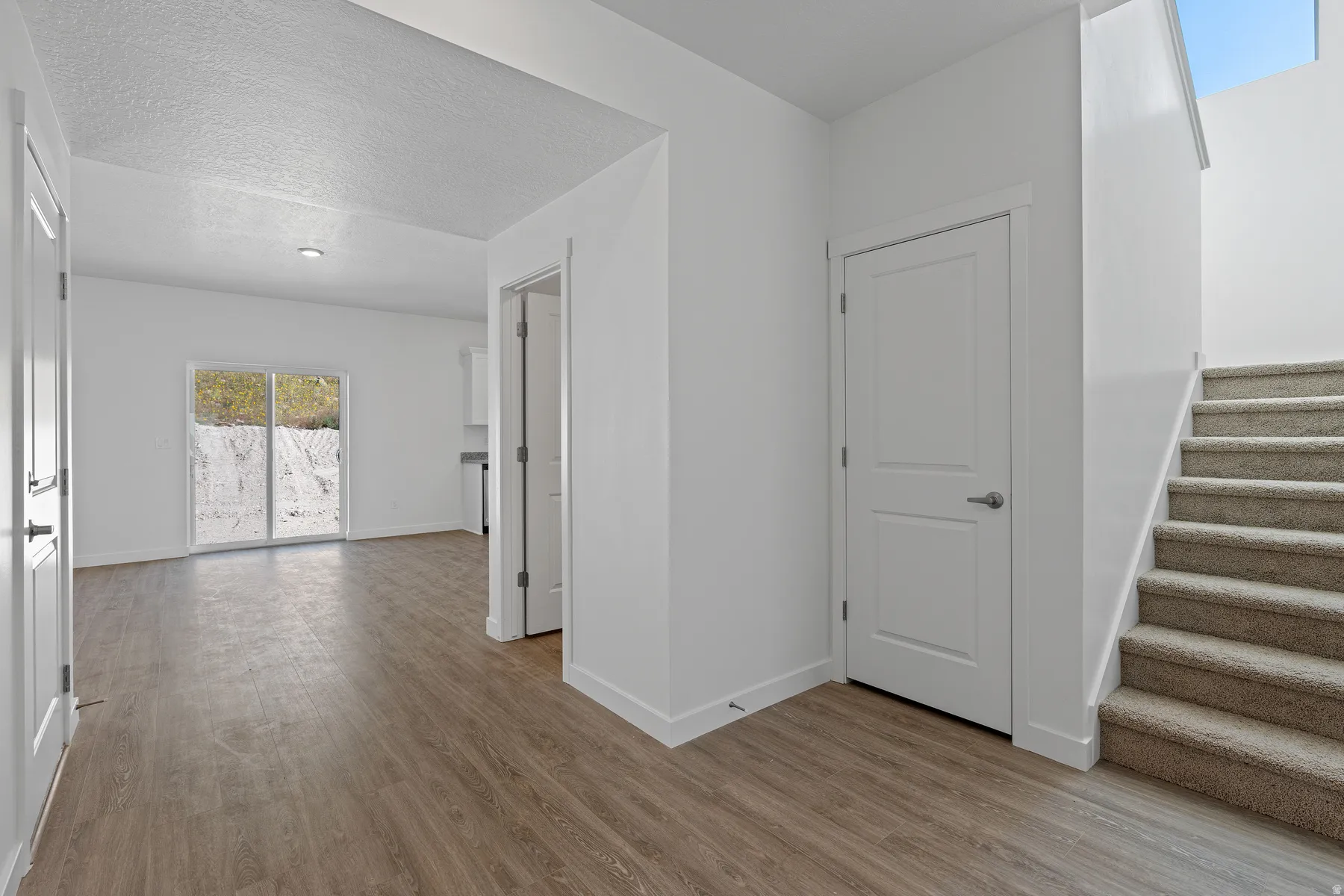 Wood-finish flooring, white paneled doors, and a carpeted staircase