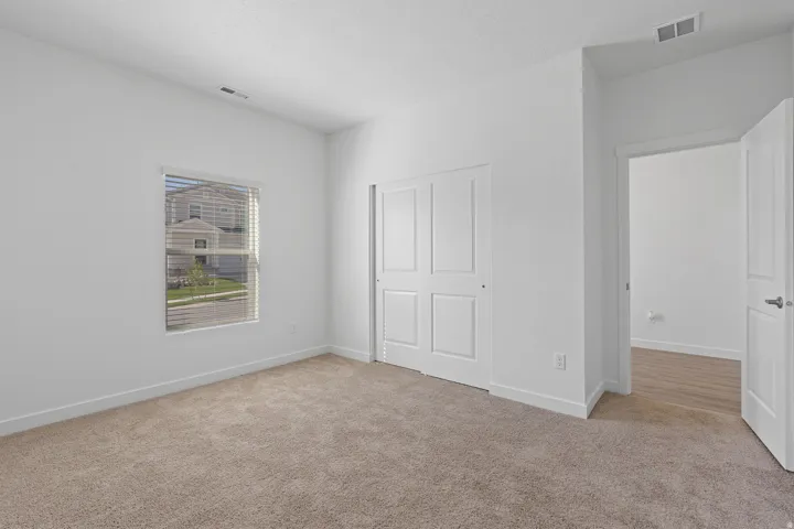 Neutral-toned carpet flooring, white walls, and a window with horizontal blinds