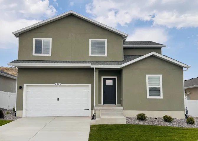 Two-story residence featuring a modern sage green exterior with white trim and board-and-batten garage doors