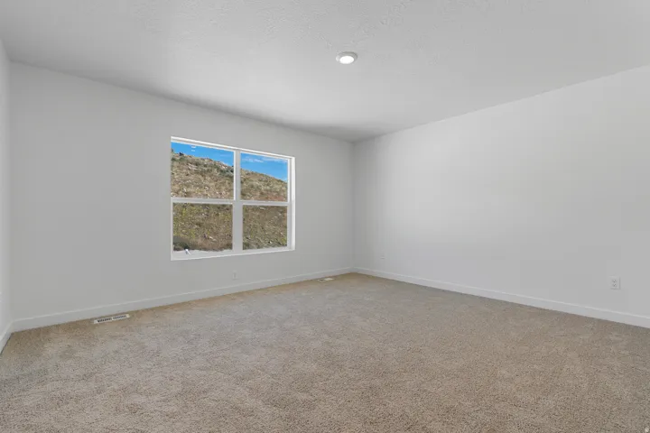 Recessed ceiling lighting, neutral carpet, white walls, and a large multi-pane window