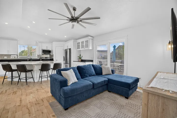 Open-concept living area with wood-finish flooring, recessed lighting, and a multi-blade ceiling fan