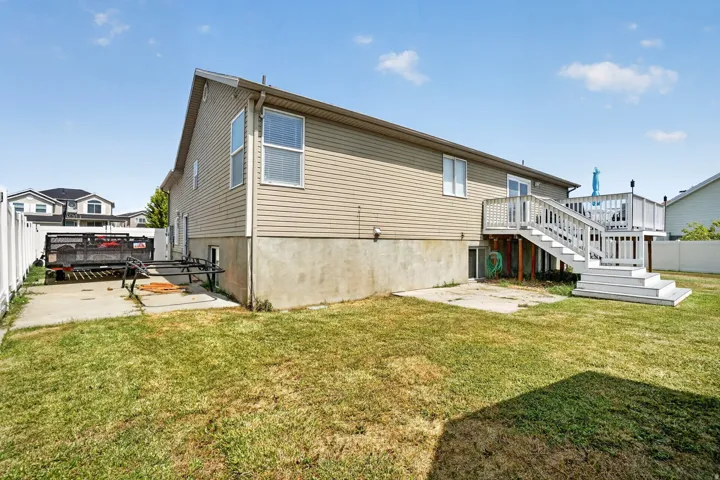 Raised rear deck with white railings and staircase, concrete patio, rv parking and fenced yard