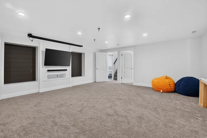 Spacious room featuring neutral carpet flooring, recessed lighting, and a built-in media center with shelving