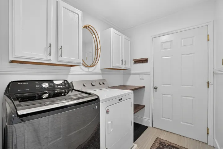 White shaker-style cabinetry, wood-finish shelving, and light-toned tile flooring