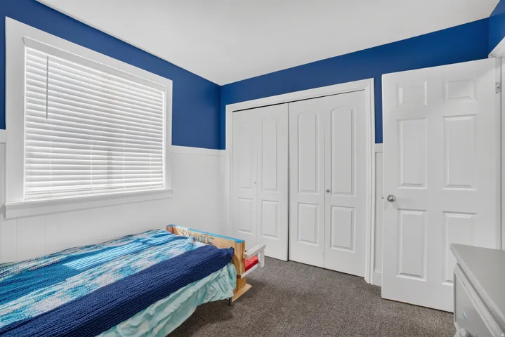 Recessed window with white blinds, white wainscoting, bi-fold closet doors, and panel-style entry door