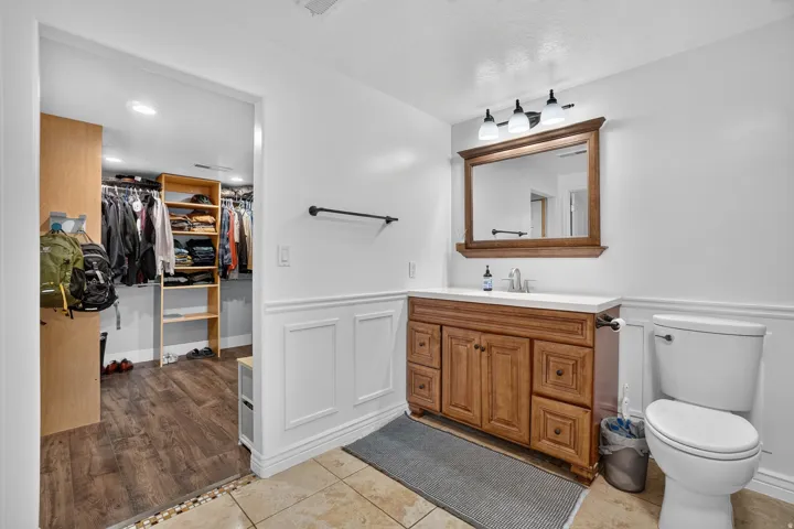 Wood-finish vanity with a light-toned countertop, framed mirror, and three-light fixture