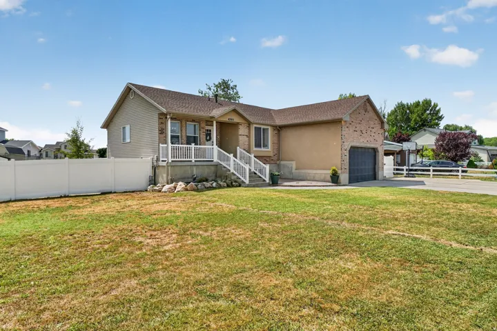 Exterior featuring brick and siding finishes, an attached garage, a front porch with white railings, and a fenced yard