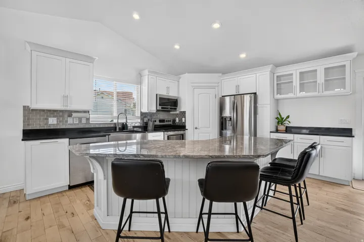 Kitchen featuring white cabinetry, stainless steel appliances, a multi-level island, recessed lighting, and wood-finish flooring