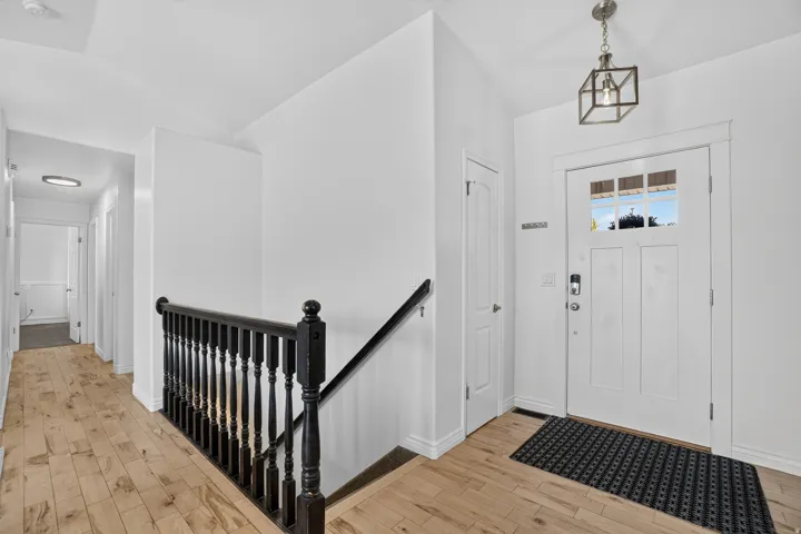 Light wood-finish flooring, white walls, and a dark wood stair railing
