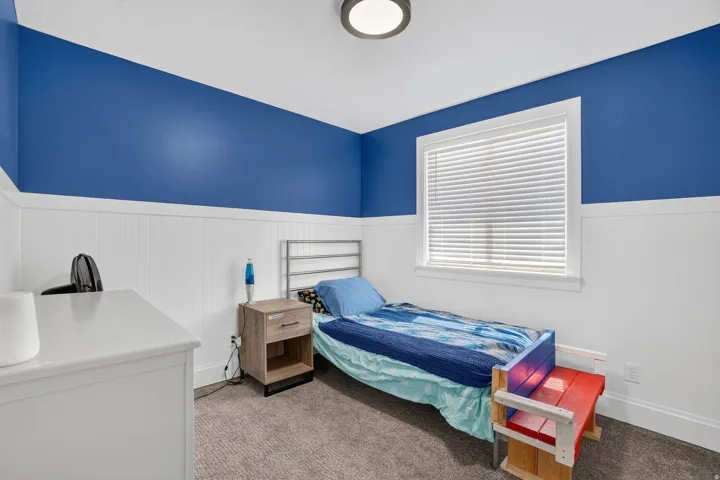 Recessed window with white blinds, wall paneling, and ceiling-mounted light fixture