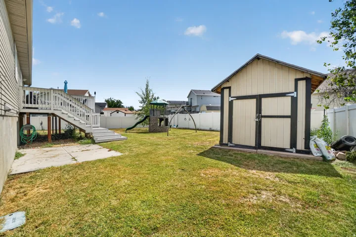 Expansive backyard featuring a detached storage shed, a multi-level deck with stairs, and a white privacy fence