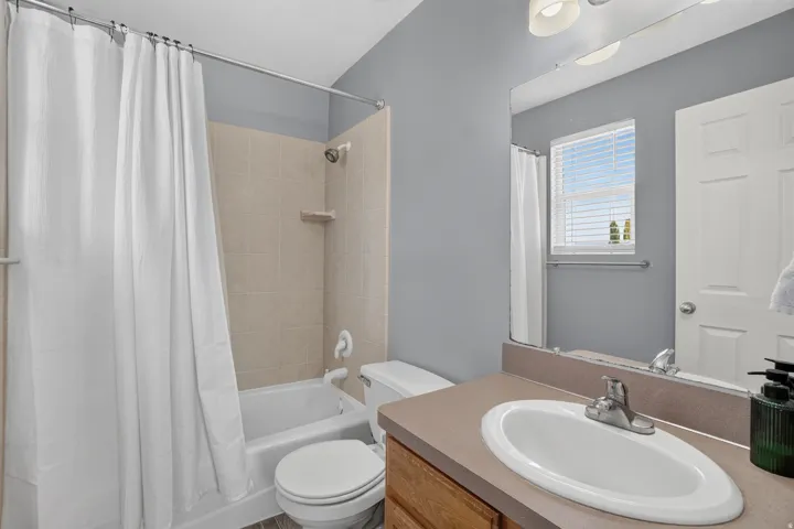 Bathroom featuring a white bathtub, ceramic tile shower surround, single vanity with oval sink, and a framed mirror