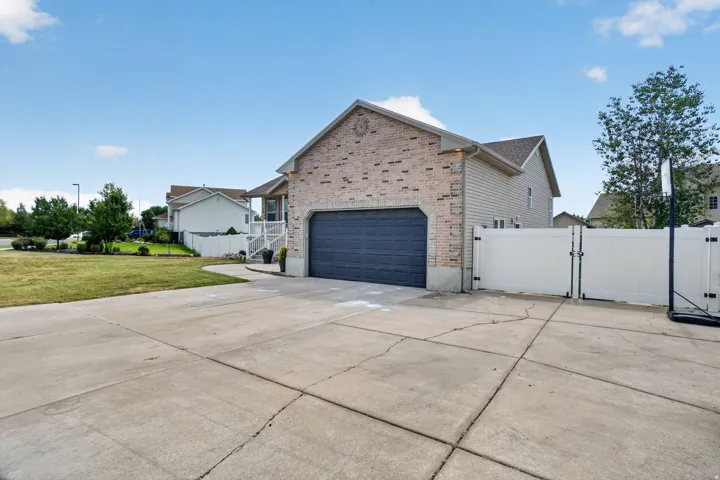 Brick and siding exterior with an attached garage, concrete driveway, and a white privacy fence