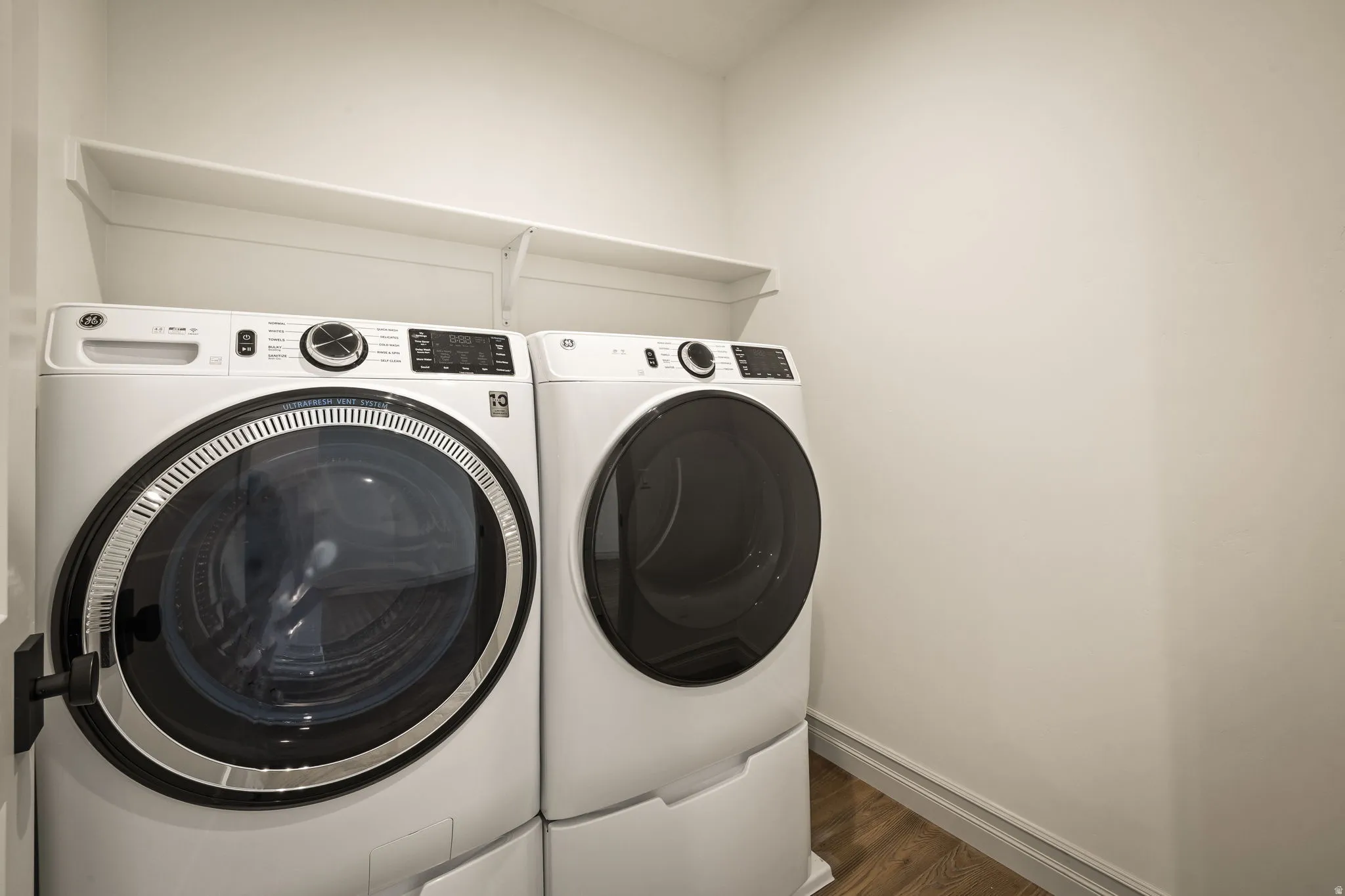 Laundry area featuring a built-in shelf, wood-finish flooring, and light-toned walls