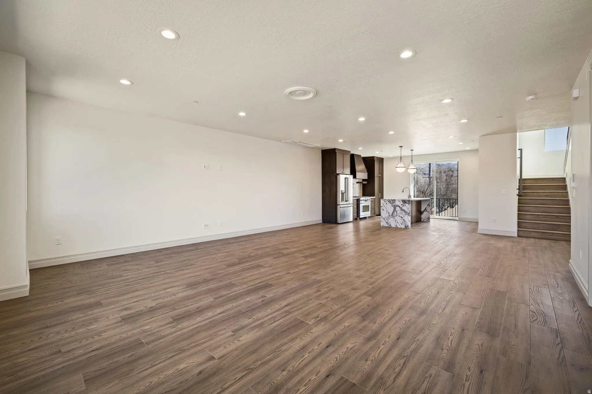 Recessed lighting illuminates wood-finish flooring throughout