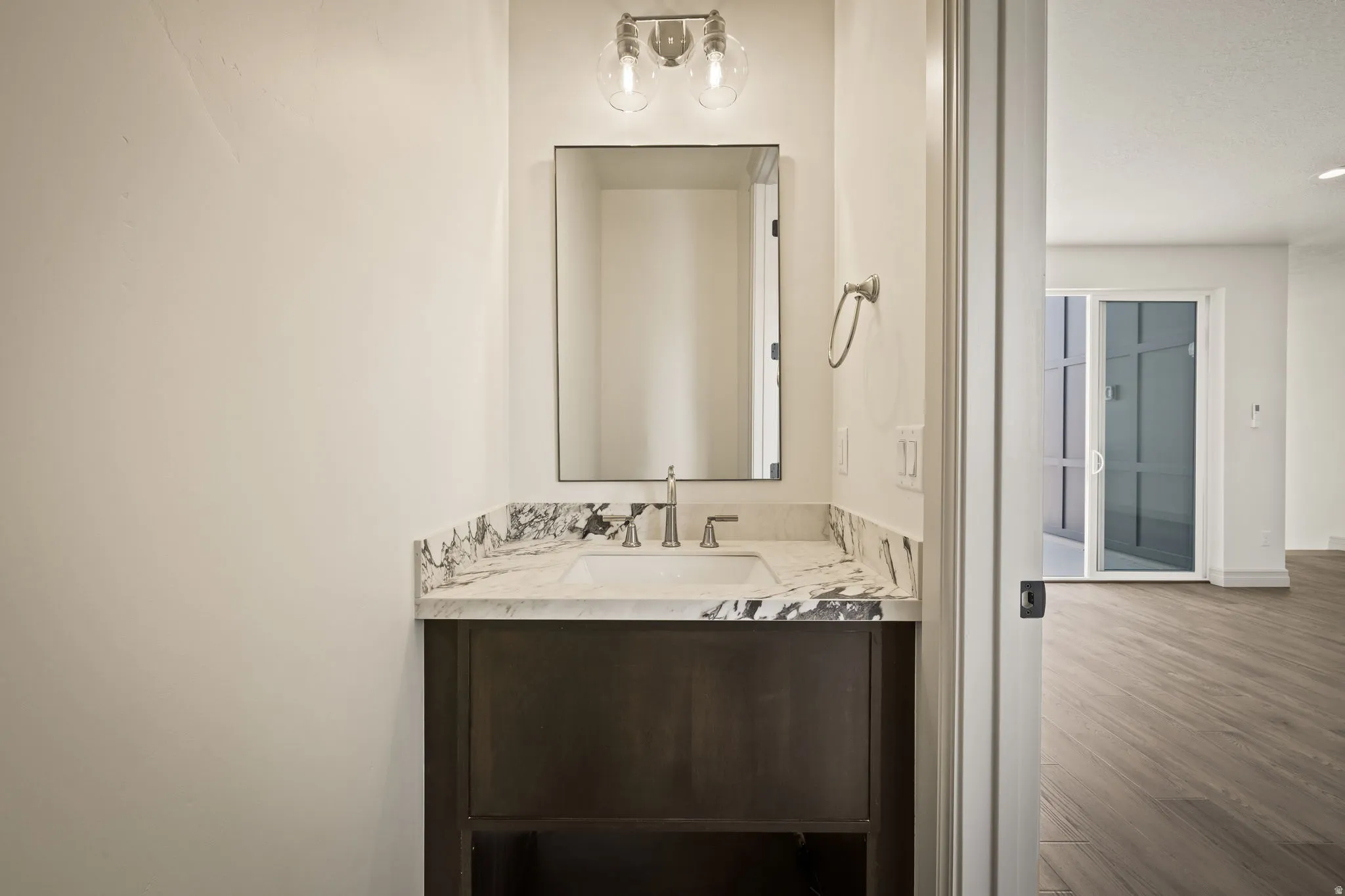 Vanity with a polished stone countertop, undermount sink, and dark wood-finish cabinetry