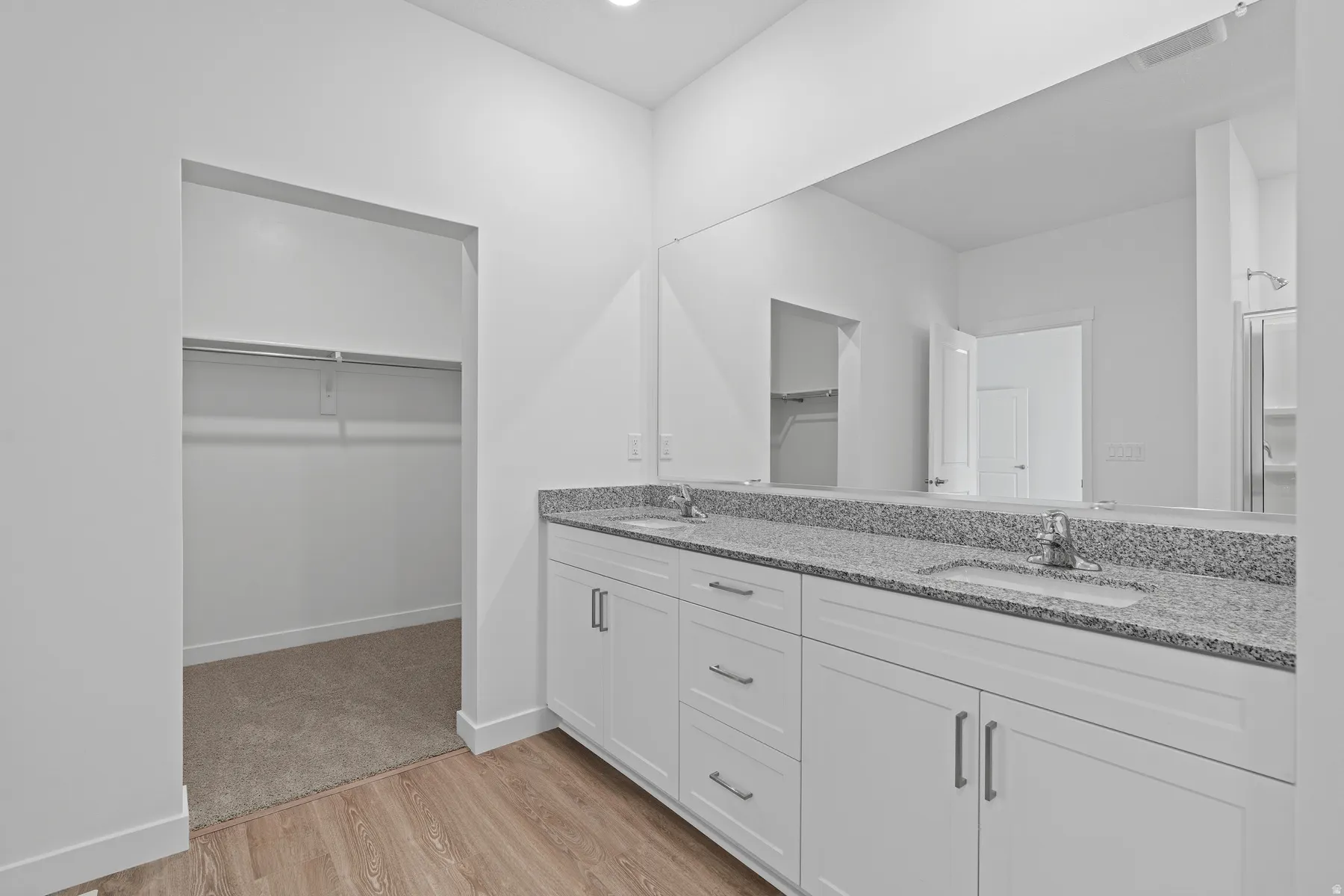 Spa-inspired primary bathroom featuring a double vanity with soft-close cabinetry, granite countertops, and polished chrome fixtures