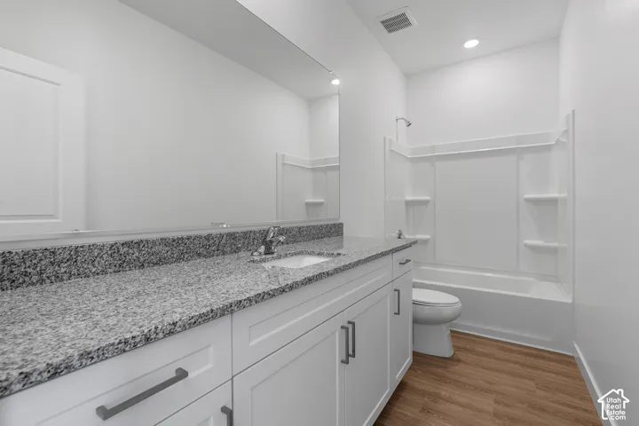Spa-inspired bathroom featuring a granite speckled countertop with dual sink vanity, white cabinetry with brushed metal hardware, and a walk-in shower with frameless glass enclosure and built-in shelving