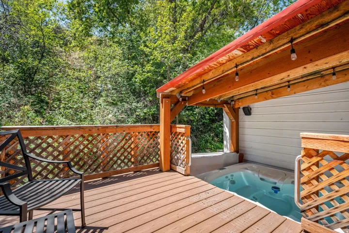 Wood-finish deck with lattice railing, built-in hot tub, and wood-beam overhead structure