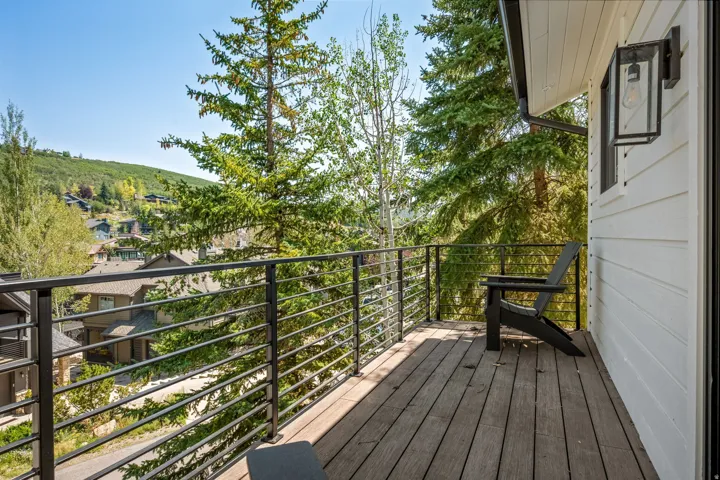 Exterior decking with horizontal metal railing, white horizontal siding, and a black exterior light fixture