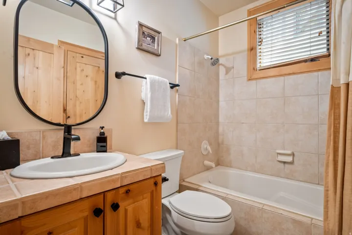 Wood vanity with black hardware, tile countertop, white undermount sink, and a black single-handle faucet