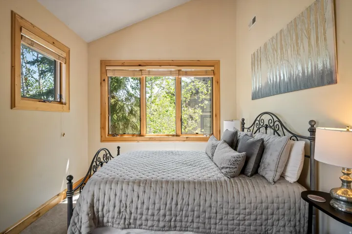 Bright bedroom with triple wood-frame windows flooding the space with natural light