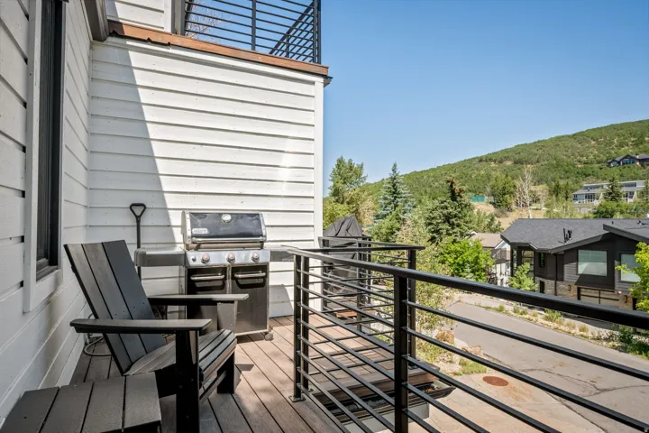Outdoor balcony featuring wood-finish decking, white horizontal siding, and a black metal railing