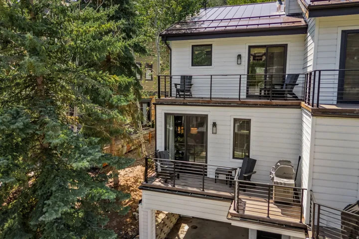 Modern three-story residence featuring clean-lined architectural design with white fiber cement siding and standing seam metal roofing