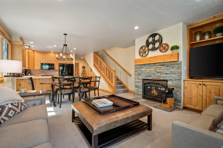 Open-concept living area featuring warm wood cabinetry, stainless steel appliances, and a gas fireplace with stone surround