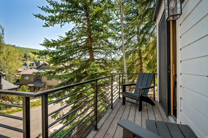 Modern composite deck with horizontal cable railing system overlooking forested landscape and hillside terrain