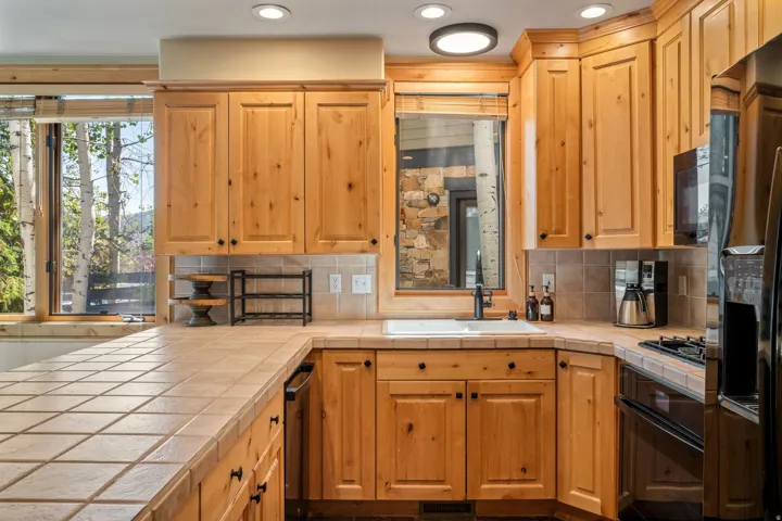 Spacious kitchen featuring warm wood cabinetry, stainless steel appliances, tile flooring, and a large center island with counter seating