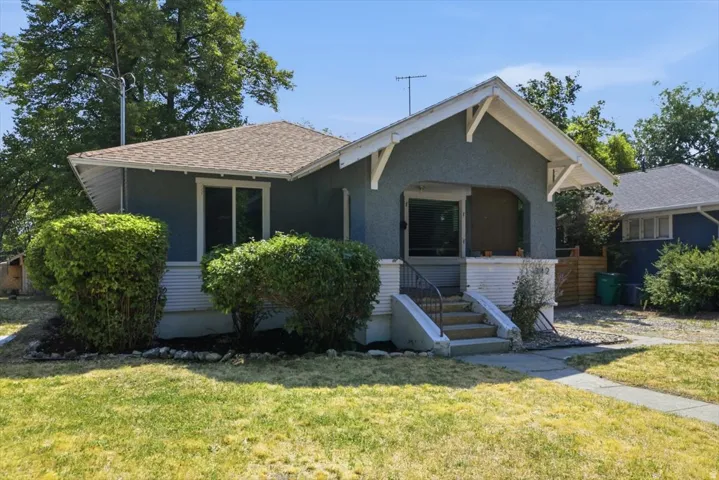 Charming bungalow featuring a covered front porch with decorative gable trim, large multi-pane windows, and a welcoming entry staircase