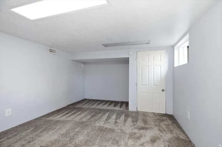 Spacious bonus room with neutral carpet flooring, recessed ceiling lighting, and abundant natural light from skylight and window