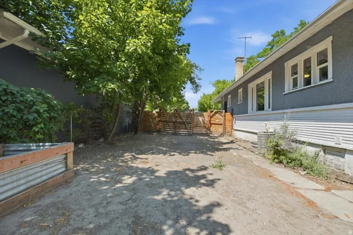 Spacious backyard with mature shade trees, wooden fencing, and direct access to the residence