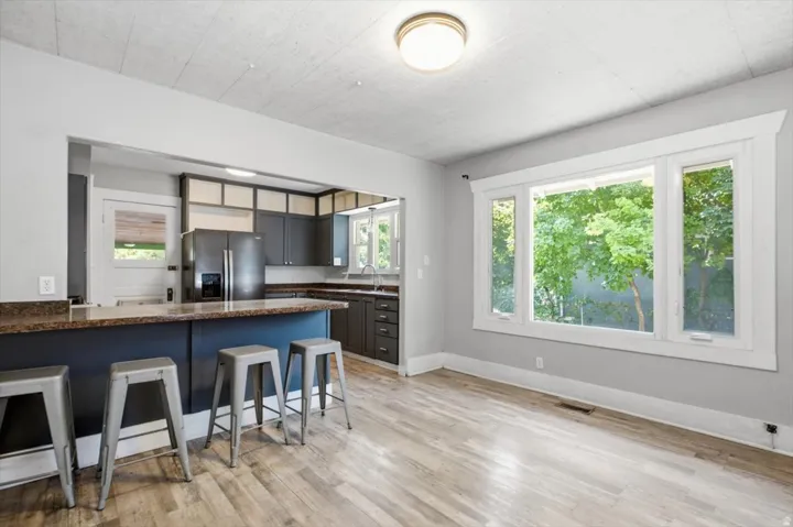 Open concept kitchen with dark cabinetry, stone-finish countertops, and wood-finish flooring