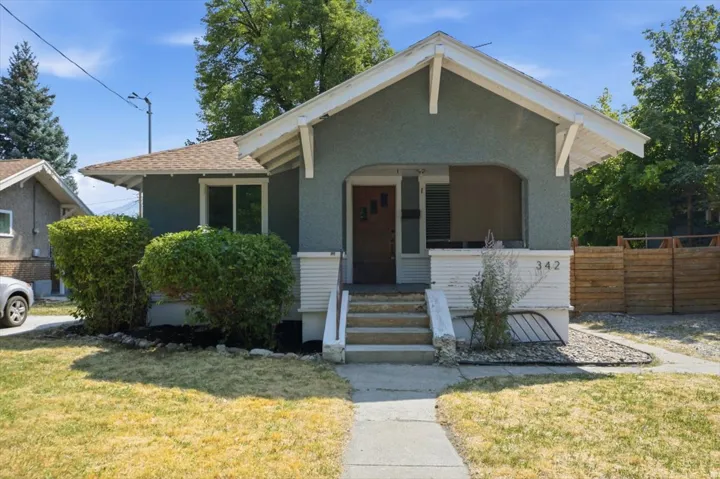 Charming bungalow featuring a gabled roofline with exposed beam detailing, front-facing arched entryway, and multi-pane windows