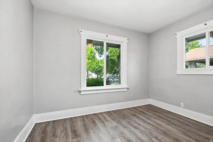 Wood-finish flooring, light gray wall paint, and multiple windows with white trim