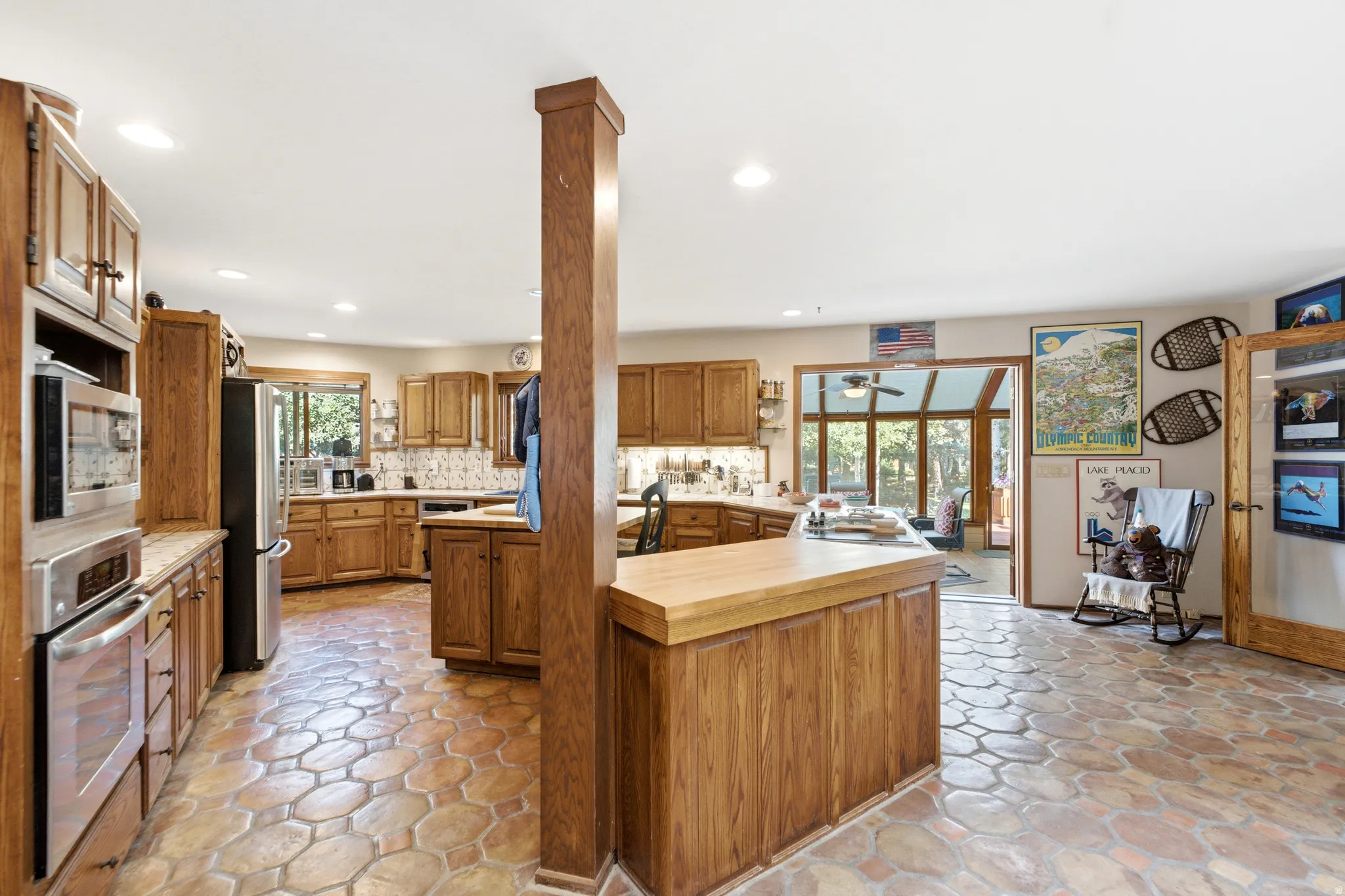 Spacious kitchen featuring extensive wood cabinetry, stainless steel appliances, recessed lighting, a built-in oven and microwave, and distinctive tile flooring